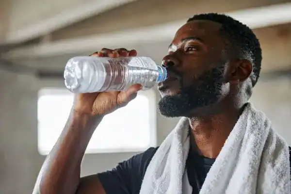 Hydration: The Secret Ingredient for a Toned Stomach and Enhanced Fitness 1 Image of man drinking water to improve hydration Birch after work out.